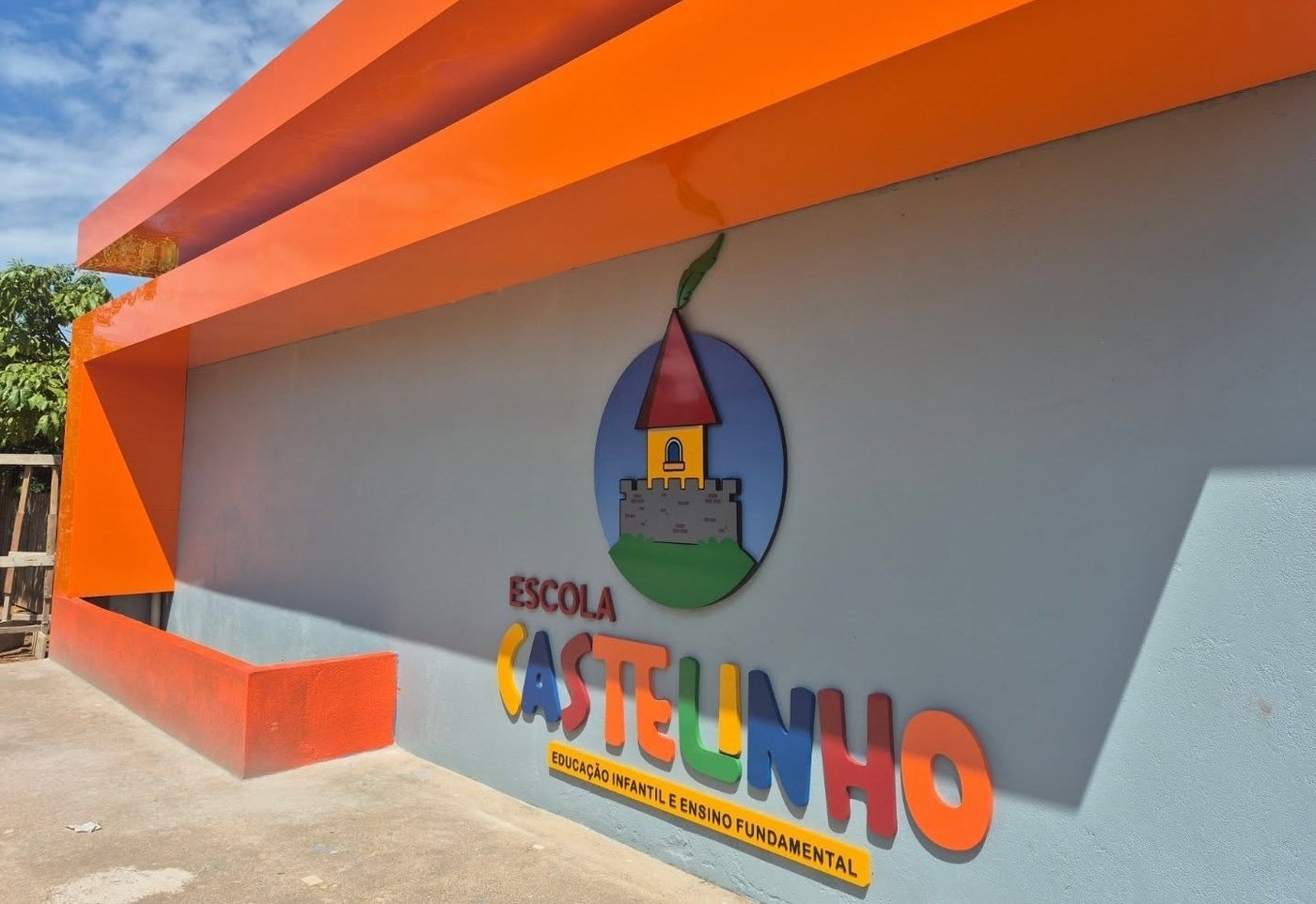 Fachada da Escola Castelinho, com a logo do castelo pintada na parede laranja e azul