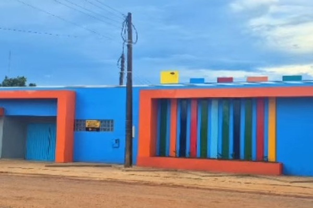 Fachada da Escola Castelinho vista de fora, com paredes azuis e laranja